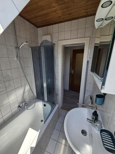 a white bathroom with a tub and a sink at FeWo Zimmer Waldmohr in Waldmohr
