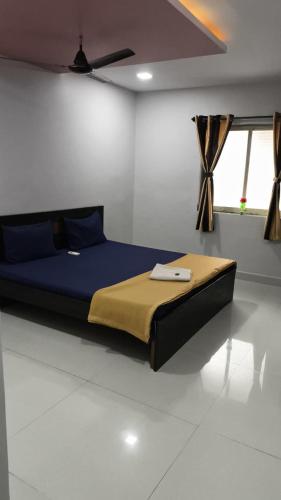 a bedroom with a bed with blue sheets and a ceiling at Hotel Radha krishna in Neral