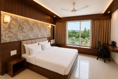 a bedroom with a large bed and a window at Hotel H F at Assagao North Goa in Assagao