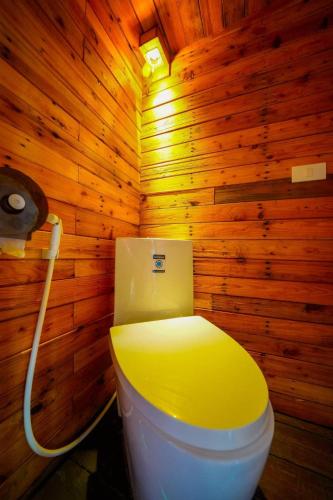 a bathroom with a yellow toilet in a wooden wall at Keereethara chiewlarn in Ban Bang Kaeo