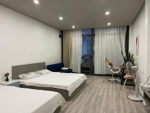a hotel room with two beds and a desk and a table at Coral Homestay Phan Rang in Kinh Dinh
