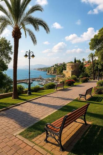 a park with benches and a palm tree and the ocean at Maxihomes Elissa in Antalya