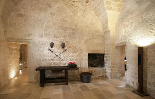 una camera con una parete in pietra, un tavolo e un camino di Dimora Storica Torre Del Parco 1419 a Lecce