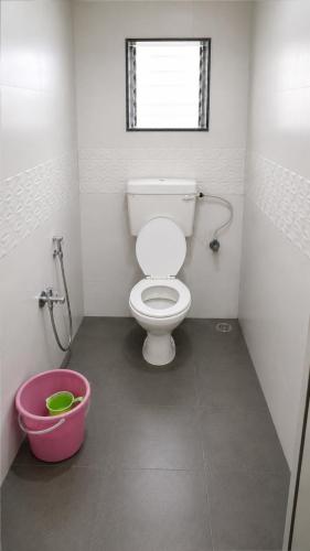 a bathroom with a toilet and a pink bucket at Hotel Radha krishna in Neral