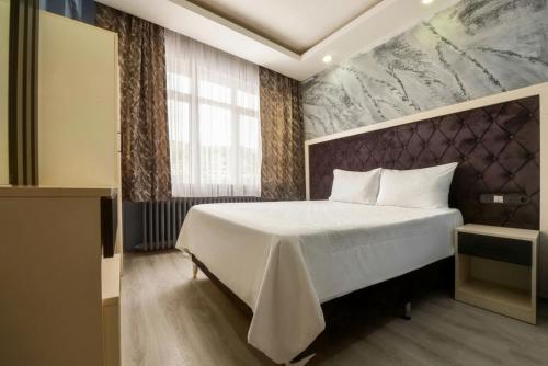 a bedroom with a white bed and a large window at Denizli Hotel in Istanbul