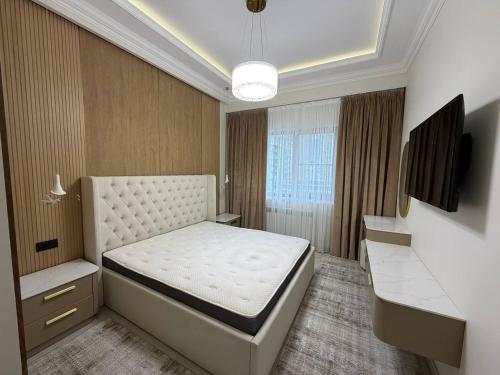 a bedroom with a white bed and a television at Top1 Gardens Residents in Tashkent
