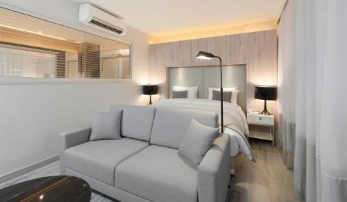 a white bedroom with a bed and a couch at Radisson Blu Belo Horizonte Savassi in Belo Horizonte