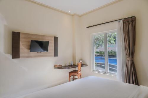 a bedroom with a bed and a desk and a window at Hotel Puri Indah & Convention in Tjakranegara