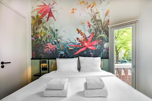 a bedroom with a large bed with a painting on the wall at Dutch Design Hotel Vondelpark in Amsterdam