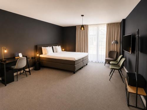 a bedroom with a bed and a desk and chairs at Boutique Hotel Zaan in Zaandijk