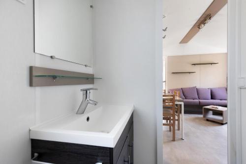 a kitchen with a sink and a living room with a purple couch at Bungalow Cap Ferret Les Lodges 3 in Lège-Cap-Ferret