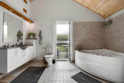 a bathroom with a white tub and a toilet at C11323-Tarm-Brombaervej-8 in Tarm