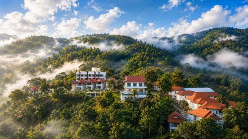 a town on a hill in the mountains with clouds at Wonderland Resort Chiangmai in Chiang Mai