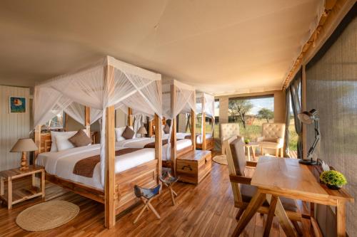 a bedroom with a four poster bed and a desk at Manya Luxury Camp in Serengeti
