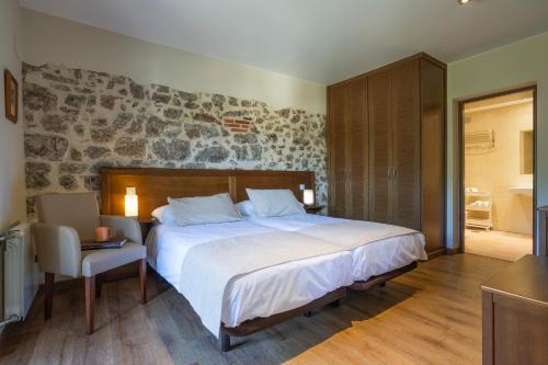 a bedroom with a large bed and a chair at La Posada del Vencejo in Alles