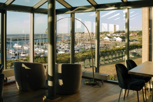 a restaurant with a view of the harbor at WestCord Hotel Schylge in West-Terschelling