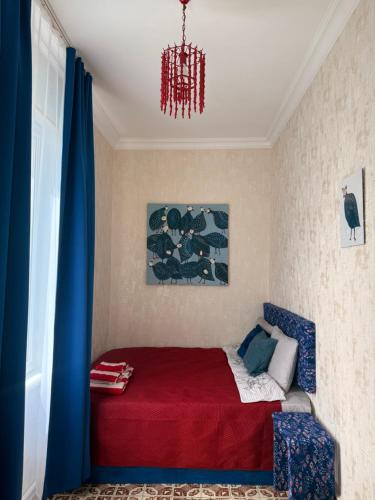 a bedroom with a bed with a red blanket and a chandelier at Mate Guesthouse in Sighnaghi