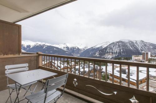 a balcony with a table and chairs and snow covered mountains at Résidence La Forêt Du Praz - Courchevel 1850 in Courchevel