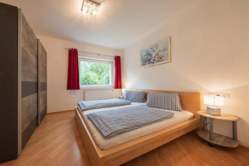 a bedroom with a bed and a window with red curtains at Stubai Apartment Telfes in Telfes im Stubai
