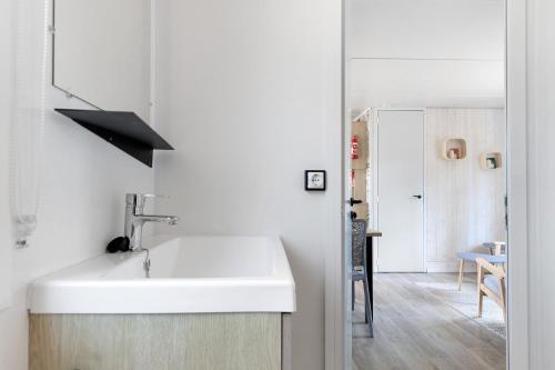 a white kitchen with a sink and a table at Bungalow Cap Ferret Les Lodges 2 in Lège-Cap-Ferret