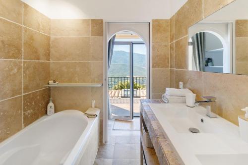 a bathroom with a tub and a sink and a mirror at Douce Heure & Saveurs in Tavaco