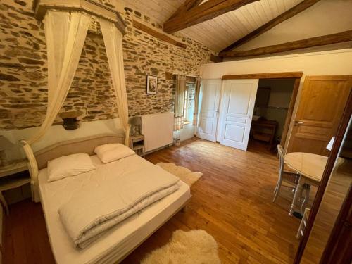 a bedroom with a bed and a stone wall at Maison d'hôtes la Passemarié in Andouque