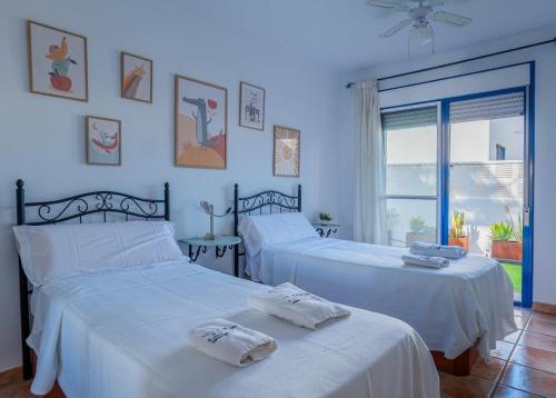 a bedroom with two beds with white sheets and a window at Casa Dracaena in San José