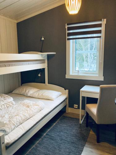 a bedroom with a bunk bed and a desk and a window at Flott hytte på Bjørgan in Grong