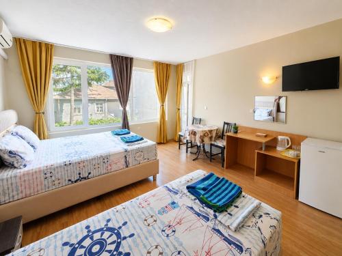 a hotel room with two beds and a desk at Kazlarov Guest House in Kiten