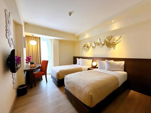 a hotel room with two beds and a desk at Atanaya Kuta Bali in Kuta
