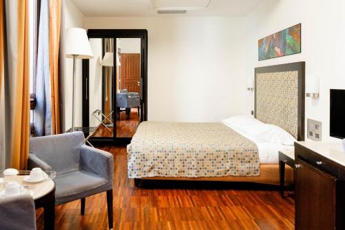 a bedroom with a bed and a chair in a room at Residenza Mecenate in Rome