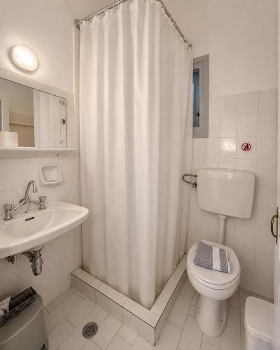 a white bathroom with a toilet and a sink at Panagiotis Rooms in Naousa