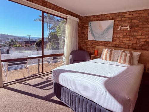 a bedroom with a bed and a large window at Ocean View Motor Inn Merimbula in Merimbula