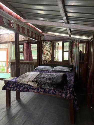 a bedroom with a bed in a room with windows at The Hojai Farmland in Hāflong