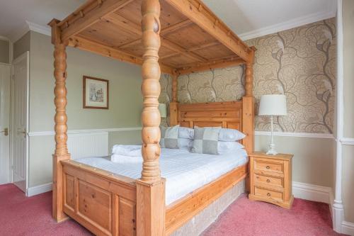a bedroom with a wooden bed with a wooden canopy at Lonsdale House in Bowness-on-Windermere