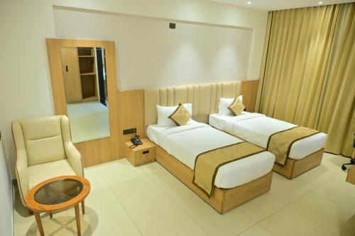 a hotel room with two beds and a chair at BHAVANIS Vista By ICON in Hosūr