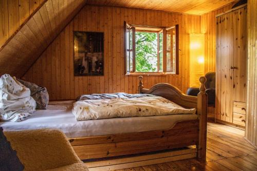 a bed in a wooden room with a window at Chata Svahovka in Malá Morávka