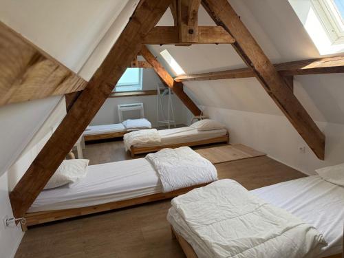 a attic room with three beds and a window at La jolie maison en grès rouge in Lagleygeolle