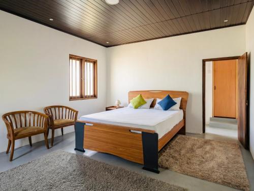 a bedroom with a large bed and two chairs at The Loons Lake Villa in Tangalle