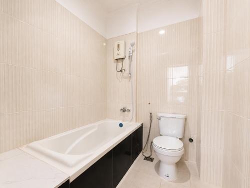 a white bathroom with a toilet and a bath tub at Champs Elysees Boutique Hotel in Phumĭ Réach Born (2)
