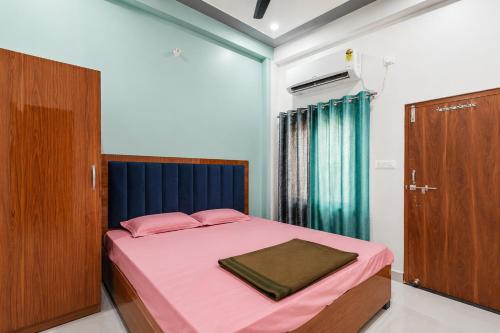 a bedroom with a bed with pink sheets and a door at Vijay Villa in Faizābād
