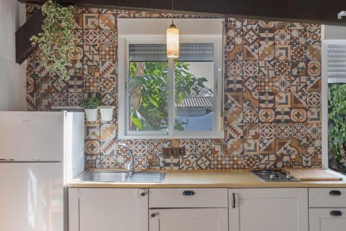 a kitchen with a tile wall with a window and a sink at Sunwaves 4 - Casa Duna in El Palmar