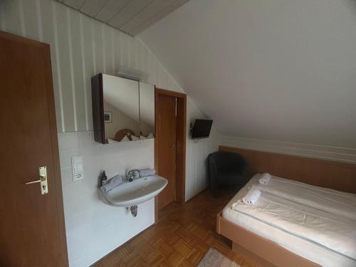 a bathroom with a sink and a bed at Pension Zimmermann in Unteruhldingen