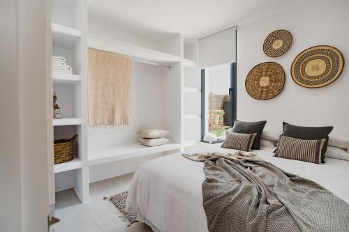 a white bedroom with a bed and a window at Canalola in Cala en Bosc