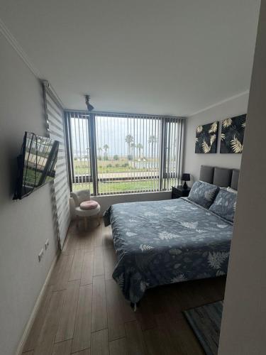 a bedroom with a bed and a large window at Bello departamento av del mar in Coquimbo