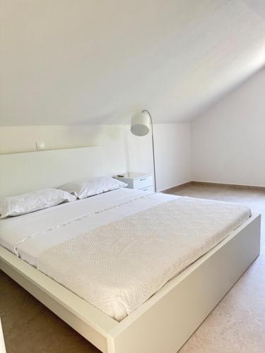a white bed in a white bedroom with a lamp at Adriatic Retreat Mljet in Polače