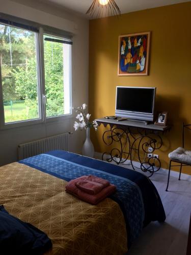a bedroom with a bed and a desk with a laptop on it at Les Acacias in La Milesse