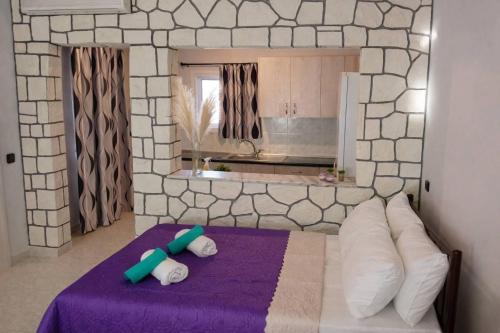 a bedroom with a purple bed with pillows and a kitchen at Domenica apartment in Salamina