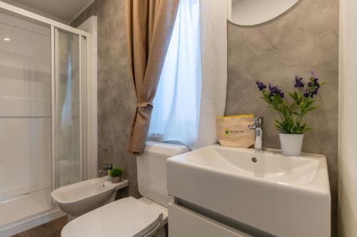 a white bathroom with a toilet and a sink at Club del Sole Viareggio Family Collection in Torre del Lago Puccini