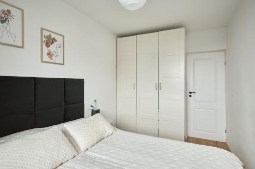 a bedroom with a white bed and white cabinets at Apartament Teatralny - Komfort w Sercu Miasta Klimatyzacja in Opole